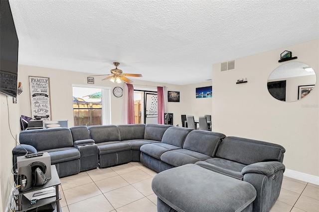 living room with a textured ceiling, light tile flooring, and ceiling fan