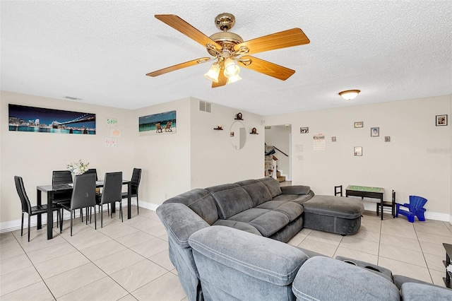 living room with ceiling fan, a textured ceiling, and light tile floors