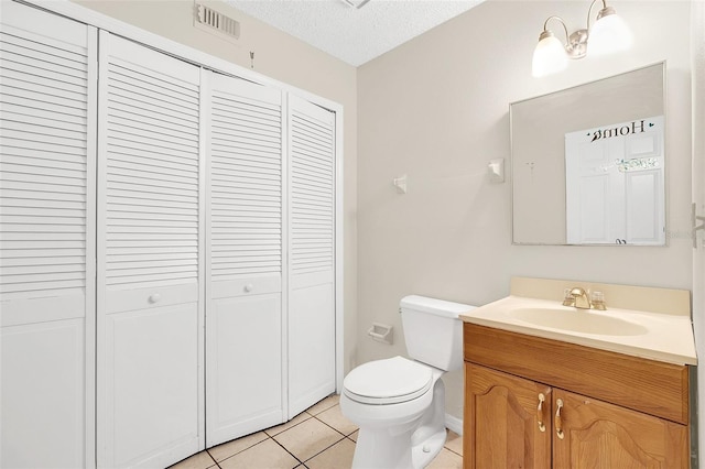 bathroom featuring tile floors, a textured ceiling, toilet, and vanity