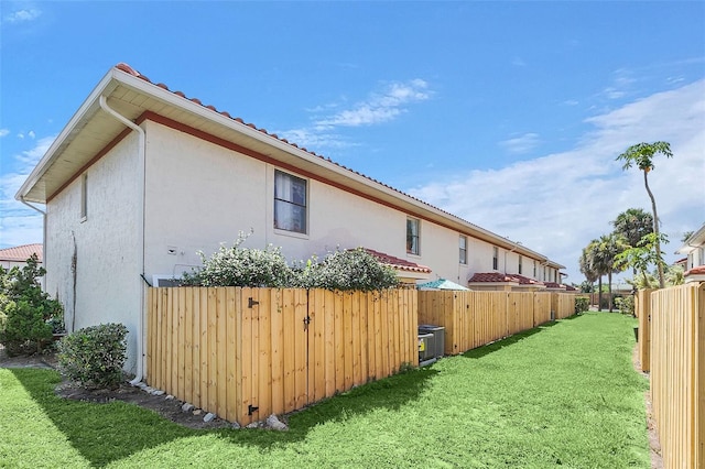 view of side of property featuring central AC and a lawn