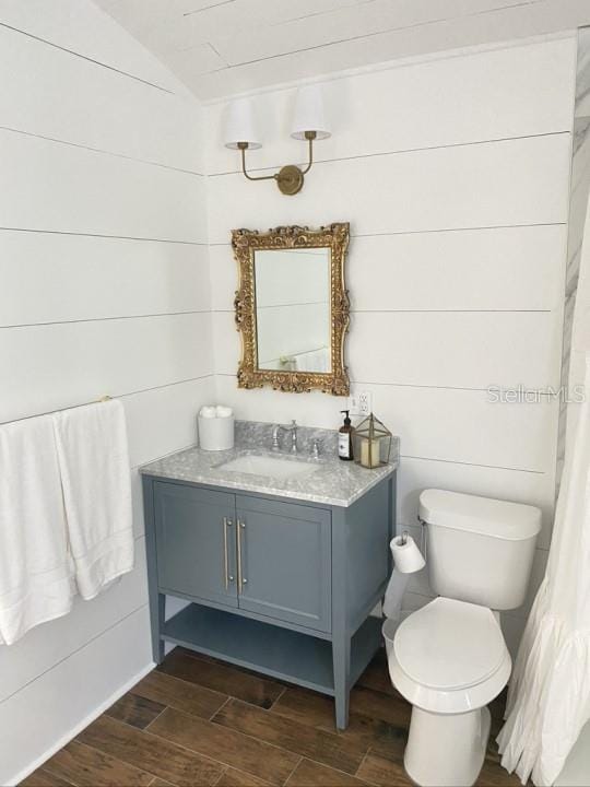 bathroom featuring lofted ceiling, wood-type flooring, vanity, and toilet