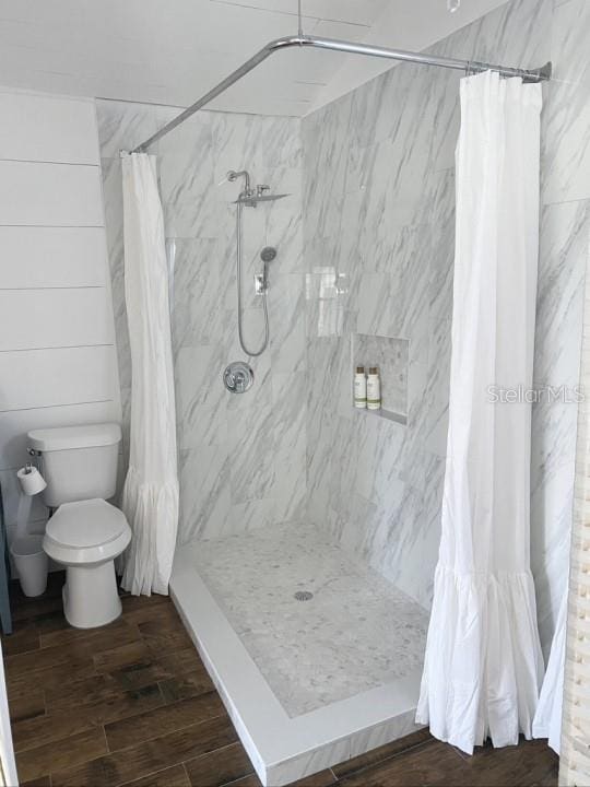 bathroom with hardwood / wood-style flooring, toilet, and a shower with shower curtain