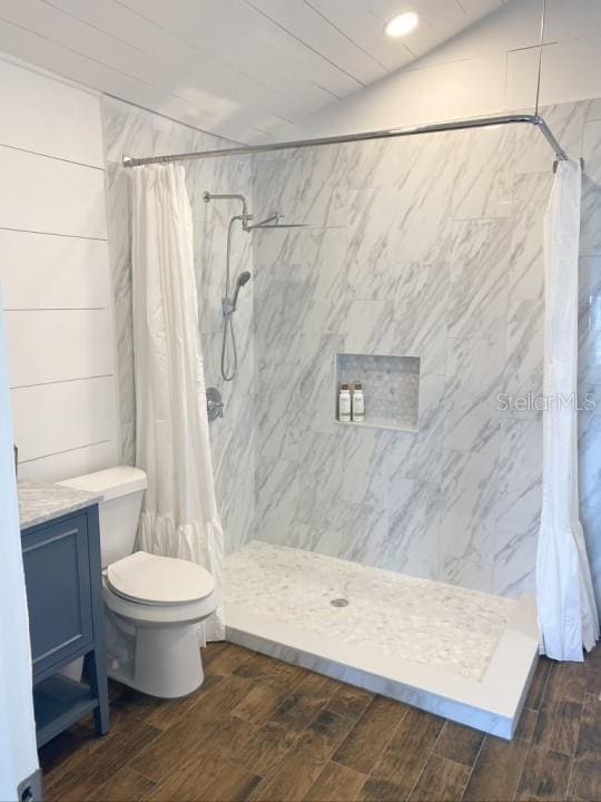 bathroom with a shower with shower curtain, toilet, hardwood / wood-style flooring, and vaulted ceiling