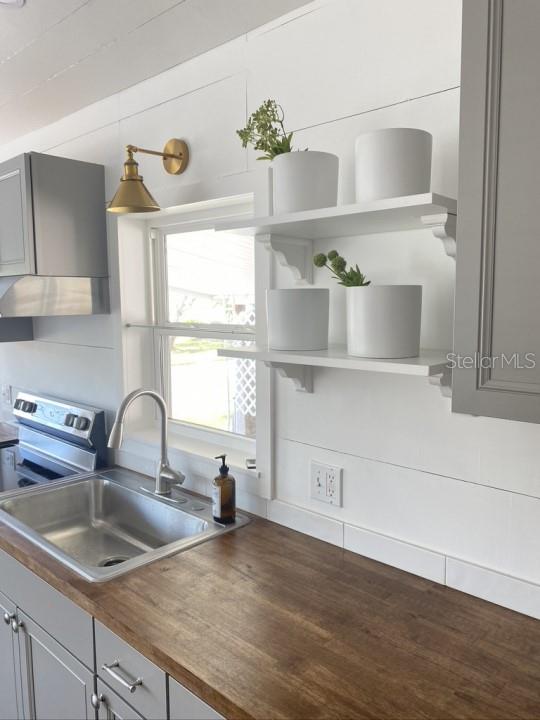 kitchen with gray cabinetry, sink, hardwood / wood-style floors, and wood counters