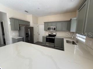 kitchen with gray cabinets, kitchen peninsula, sink, and appliances with stainless steel finishes