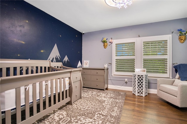 bedroom featuring baseboards, wood finished floors, and an accent wall