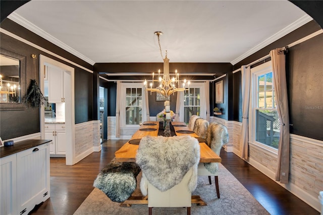 dining area featuring dark wood-type flooring, an inviting chandelier, ornamental molding, and wainscoting