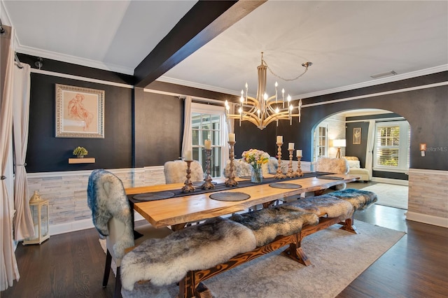 dining space featuring arched walkways, visible vents, a wainscoted wall, and wood finished floors