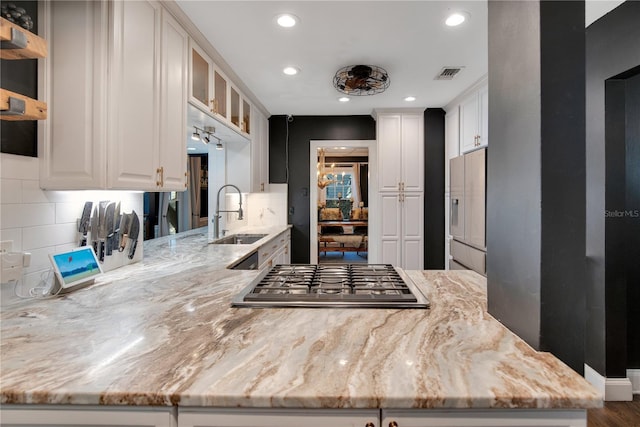 kitchen with light stone counters, visible vents, gas stovetop, white cabinets, and white refrigerator with ice dispenser