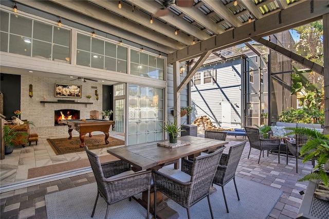 view of patio / terrace with a lanai, outdoor dining space, and an outdoor living space with a fireplace