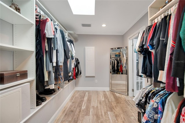 walk in closet featuring light wood-type flooring, visible vents, and a skylight