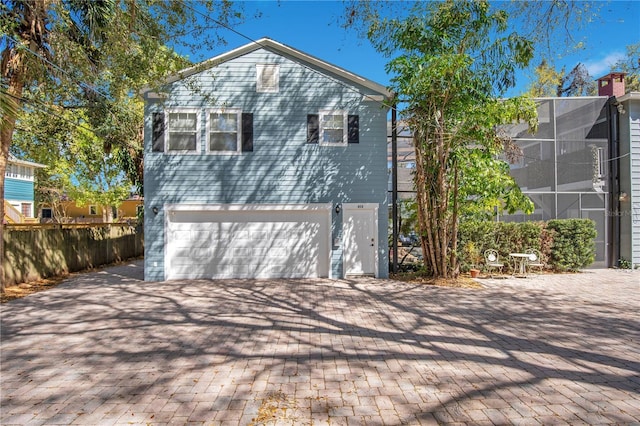 exterior space with decorative driveway, a lanai, an attached garage, and fence