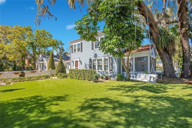 rear view of property featuring a lawn and fence