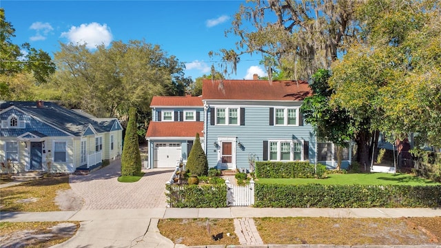 view of front of property featuring a front lawn, decorative driveway, fence, and a garage