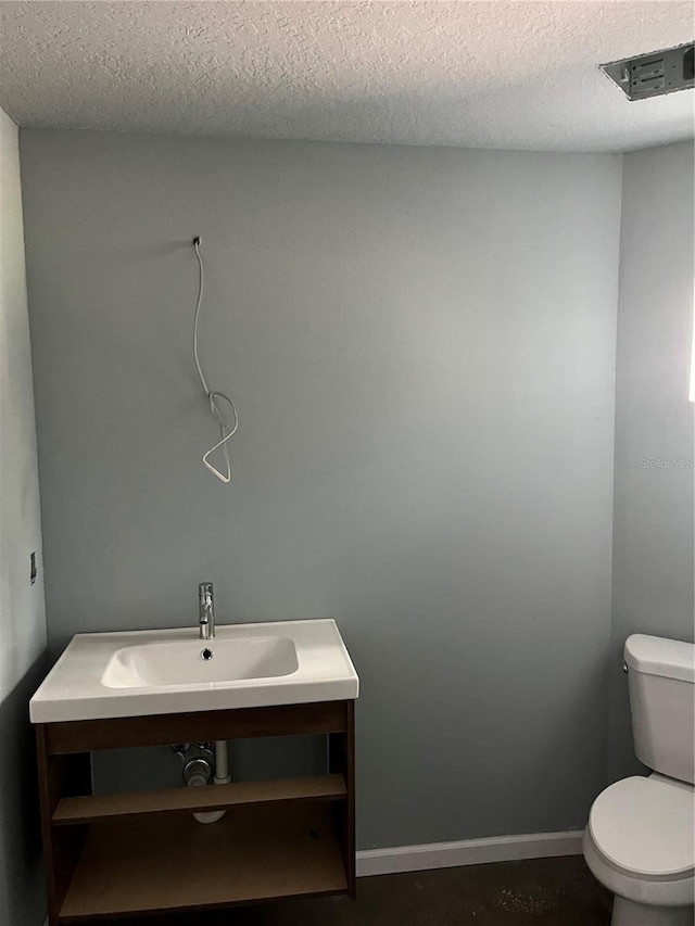 bathroom featuring a textured ceiling, toilet, and sink