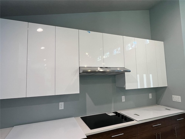 kitchen with white cabinets, dark brown cabinetry, black electric cooktop, and lofted ceiling