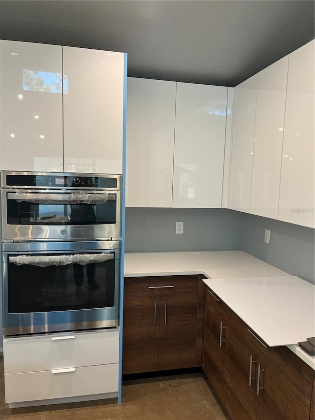 kitchen featuring white cabinets, dark brown cabinets, and double oven