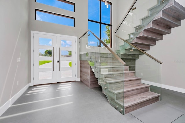 foyer with a towering ceiling, french doors, and concrete floors