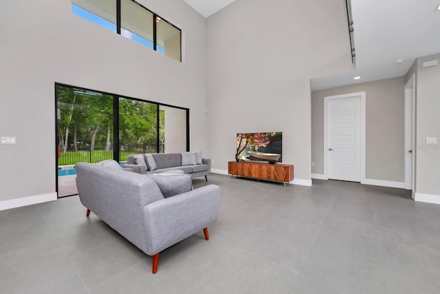 living room with a towering ceiling, track lighting, and tile flooring