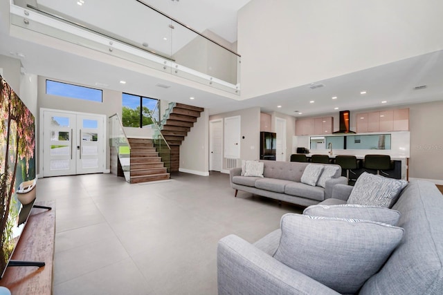 living room featuring a towering ceiling, french doors, sink, and light tile floors