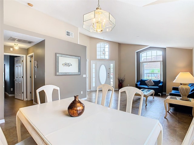 dining room featuring plenty of natural light, a towering ceiling, hardwood / wood-style flooring, and a notable chandelier