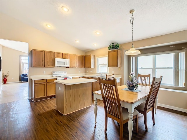 kitchen with decorative light fixtures, vaulted ceiling, dark hardwood / wood-style floors, a center island, and white appliances