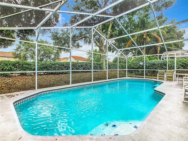 view of swimming pool featuring a patio and glass enclosure