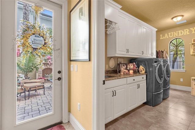 clothes washing area featuring cabinets, separate washer and dryer, and a textured ceiling