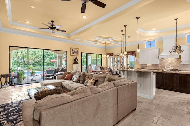 living room featuring a tray ceiling, ceiling fan with notable chandelier, and ornamental molding