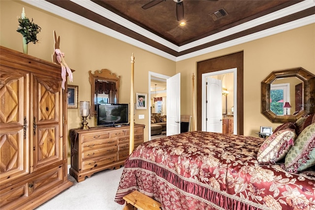 bedroom featuring carpet flooring, ceiling fan, a raised ceiling, ensuite bathroom, and ornamental molding