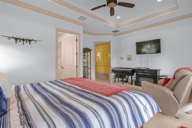 bedroom featuring ceiling fan, ensuite bathroom, crown molding, light colored carpet, and a tray ceiling