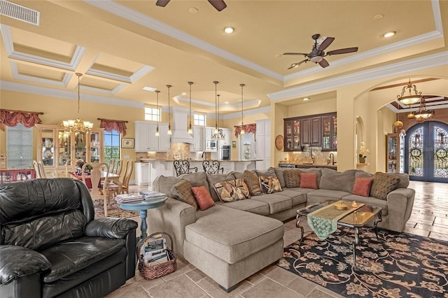 living room with beamed ceiling, ceiling fan with notable chandelier, ornamental molding, and coffered ceiling