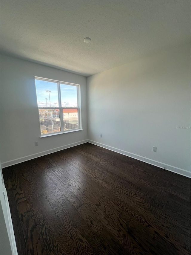 spare room with dark hardwood / wood-style floors and a textured ceiling