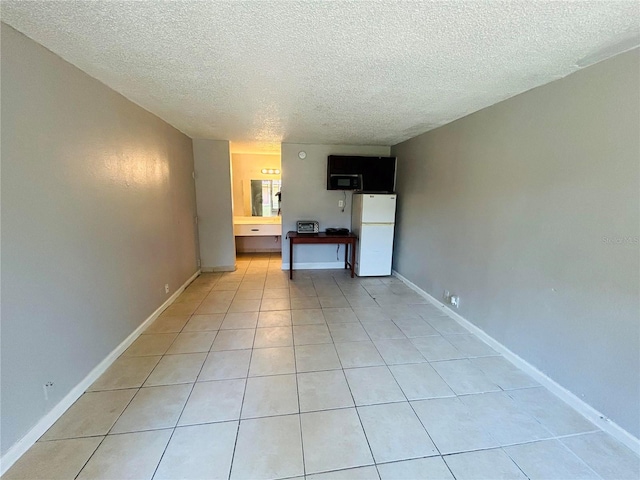 unfurnished living room with a textured ceiling and light tile floors