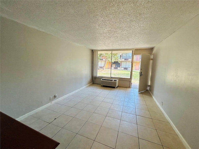 tiled empty room with a textured ceiling and a wall mounted air conditioner