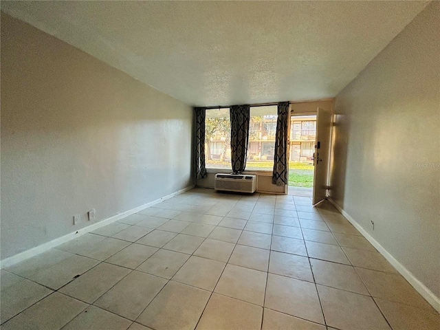 tiled empty room with a wall mounted AC and a textured ceiling