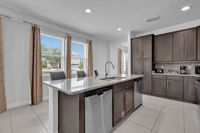 kitchen featuring decorative backsplash, dishwasher, a center island with sink, and sink