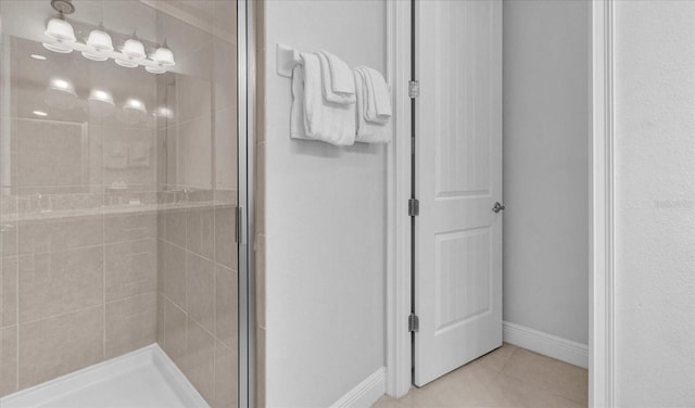 bathroom with tiled shower and tile patterned flooring