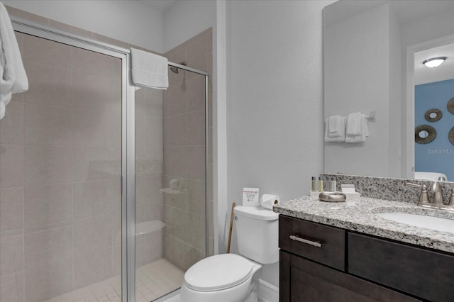 bathroom featuring vanity, toilet, and a shower with shower door