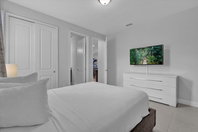 bedroom featuring a textured ceiling, a closet, and light tile patterned flooring