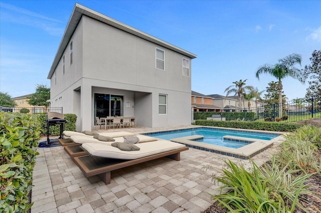 rear view of property featuring a swimming pool with hot tub and a patio