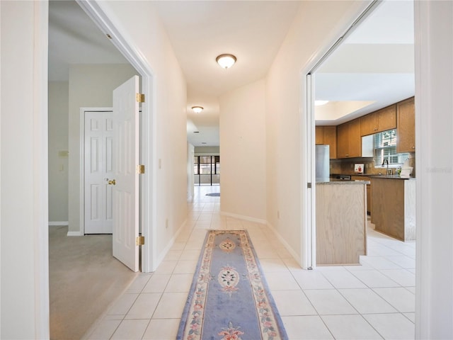 hall with plenty of natural light, sink, and light carpet