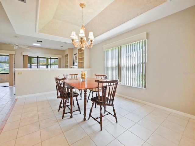 tiled dining room featuring a raised ceiling and ceiling fan with notable chandelier