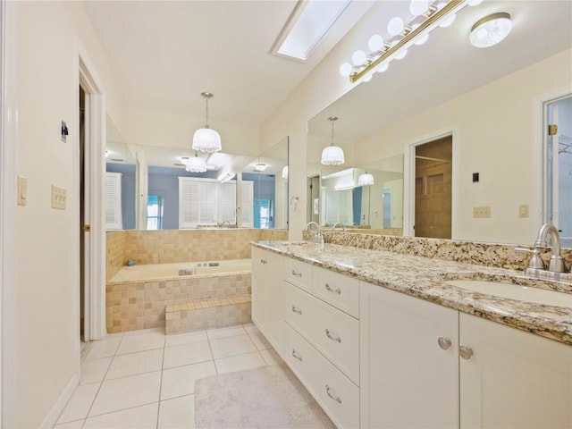 bathroom featuring tiled bath, a skylight, tile patterned flooring, and vanity