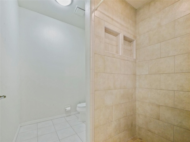 bathroom featuring tiled shower, tile patterned flooring, and toilet