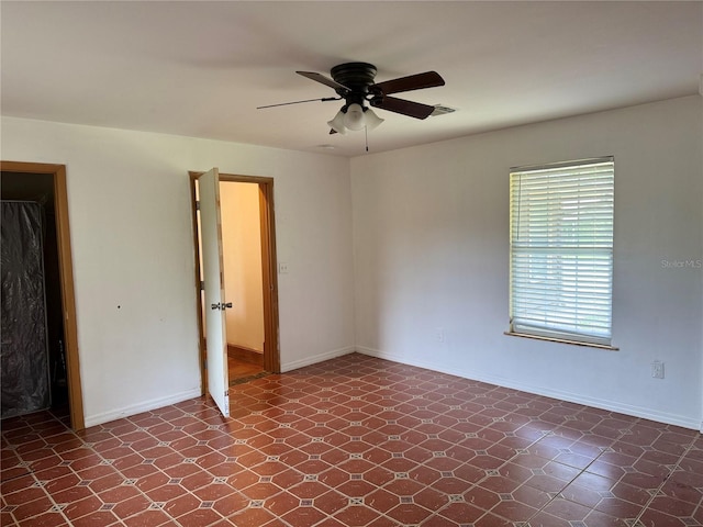 unfurnished room with dark tile floors and ceiling fan