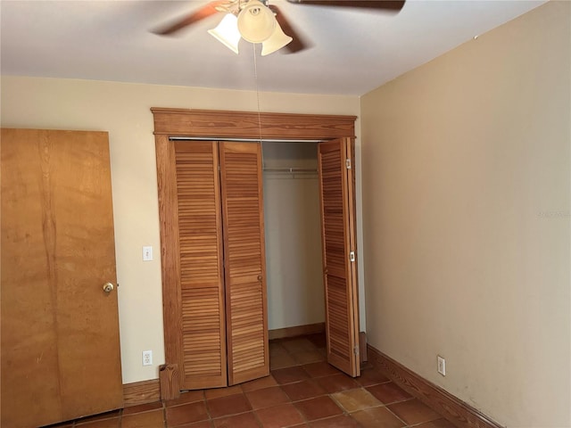 unfurnished bedroom featuring dark tile flooring, ceiling fan, and a closet