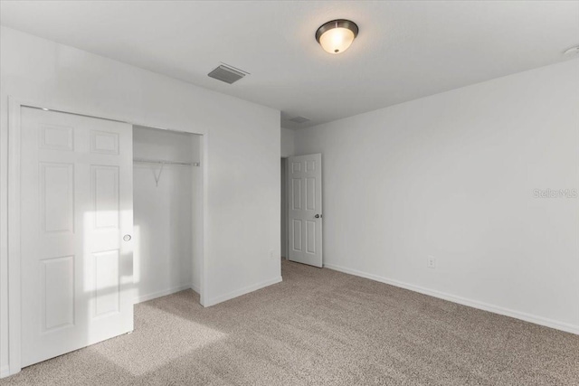 unfurnished bedroom with light colored carpet and a closet