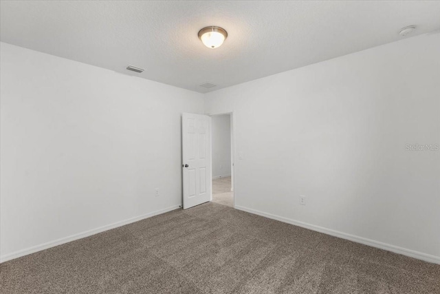 carpeted empty room with a textured ceiling