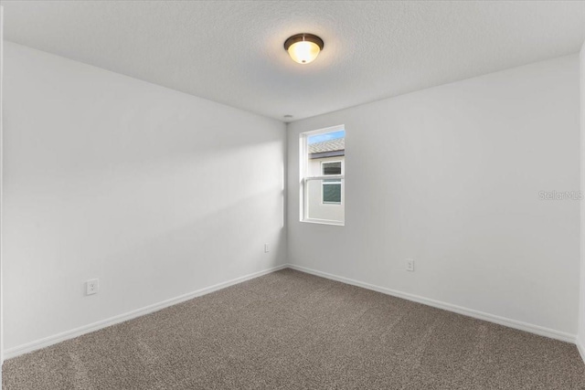 carpeted empty room featuring a textured ceiling